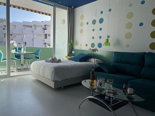 a bedroom with a bed and a couch and a table at LAHOLA Glam Suites in Torremolinos
