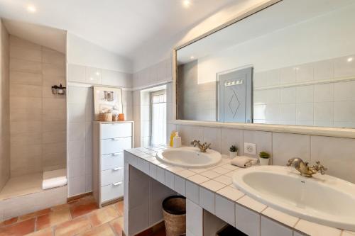 a bathroom with two sinks and a large mirror at Mas Oréa Sous la glycine in Gordes