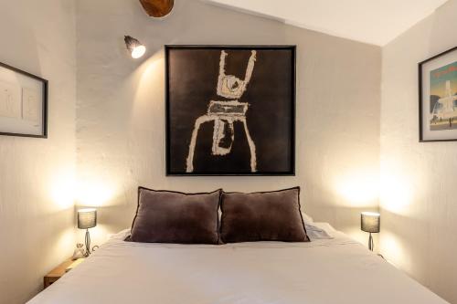1 dormitorio con 1 cama con una pintura en la pared en Mas Oréa Sous la glycine en Gordes