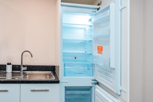 a kitchen with an empty refrigerator with a sink at Entire 2 Bedrooms and 2 Bathroom Apartment in Manchester City -Free underground Parking in Manchester