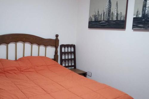 a bedroom with a bed with an orange comforter at La verde de Playa in Playa Unión