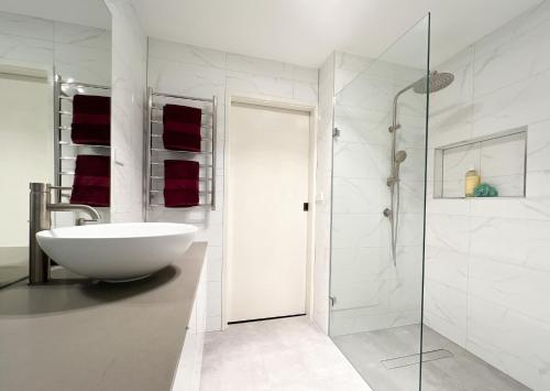 La salle de bains blanche est pourvue d'un lavabo et d'une douche. dans l'établissement The Swan Lakehouse, on Budgewoi Lake, à Budgewoi