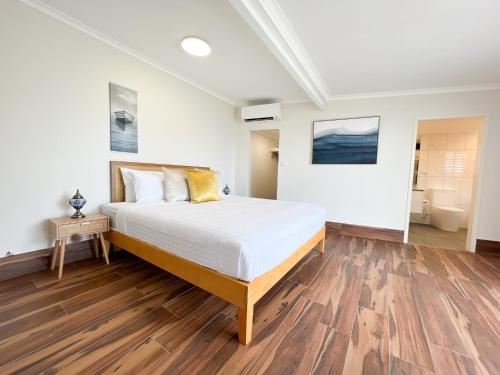 - une chambre avec un grand lit et du parquet dans l'établissement The Swan Lakehouse, on Budgewoi Lake, à Budgewoi