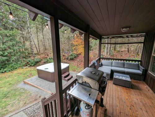 a screened in porch with a grill and a couch at River Rock Chalet :: Hot Tub, Pets, Stevens Pass in Skykomish