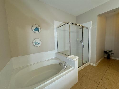 La salle de bains est pourvue d'une baignoire et d'une douche en verre. dans l'établissement Vista Cay Getaway Luxury Condo by Universal Orlando Rental, à Orlando