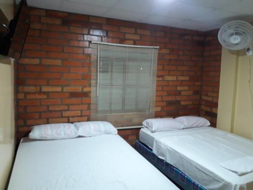 2 letti in una camera con muro di mattoni di HOTEL EL CASTILLO MANTA2 a Manta