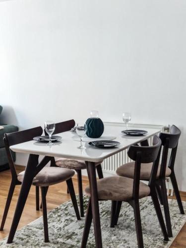 a white table with four chairs and wine glasses at Tuse Lux apartments in Skopje
