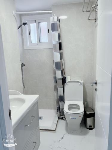 a white bathroom with a toilet and a sink at San Eugenio in Adeje