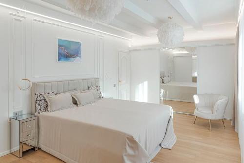 biała sypialnia z dużym łóżkiem i krzesłem w obiekcie 252 m² luxury 4 bedroom house in the pine-forest w Wilnie