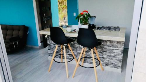 une cuisine avec deux chaises noires au comptoir dans l'établissement Reserva La Esperanza, à Vergara
