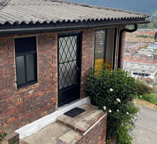 a brick house with a window and a bush at Alojamiento/Lodging:El Indio Ese in Sopo
