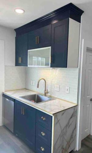 a kitchen with blue cabinets and a sink at Charming 3BR, 1BA Near Heart of Boston! in Watertown