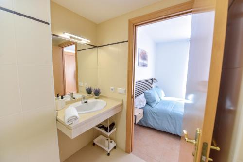 ein Bad mit einem Waschbecken, einem Bett und einem Spiegel in der Unterkunft New Premium Apartment - Free Parking & Pools in La Algaba