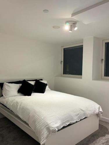 a white bedroom with a bed with black pillows at Stylish Central Escape in Sheffield