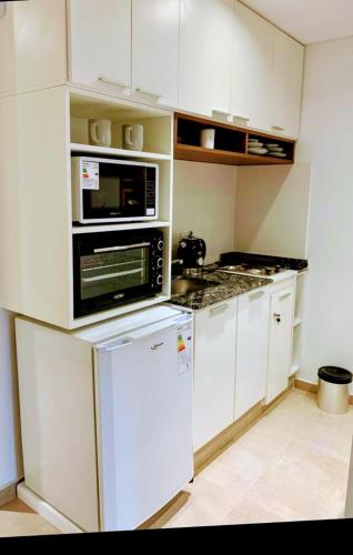 a kitchen with white cabinets and a microwave and a refrigerator at TERRA-BARRIO NORTE in San Miguel de Tucumán