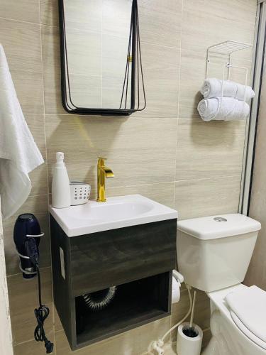 uma casa de banho com um lavatório, um espelho e um WC. em Apartaestudio Turbaco em Turbaco