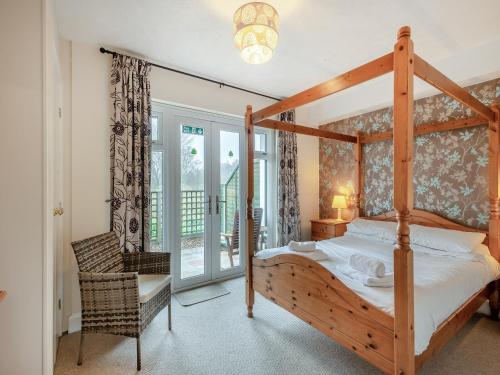 a bedroom with a wooden canopy bed and a chair at Wanderer in Sutton