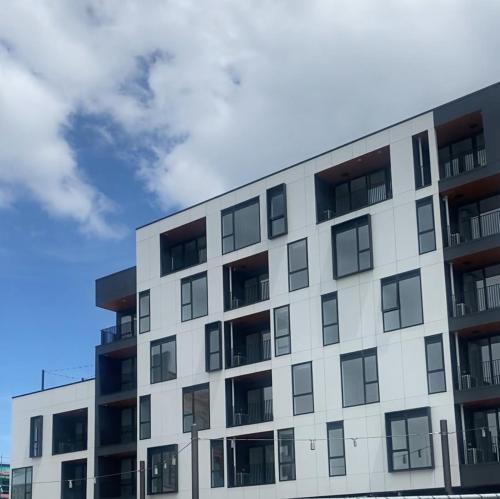 a white apartment building with a cloudy sky in the background at Cityscape, Apartment with carpark in Christchurch