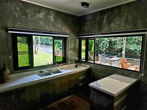 cocina con fregadero y 2 ventanas en Rugading Riverside Villa near Kota Kinabalu. en Kampong Rugarding