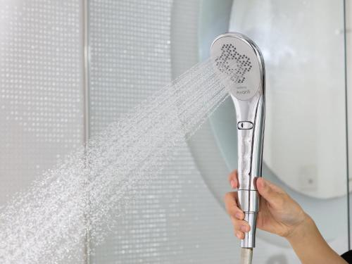 a person holding a shower brush in front of a window at APA Hotel Ishigakijima in Ishigaki Island