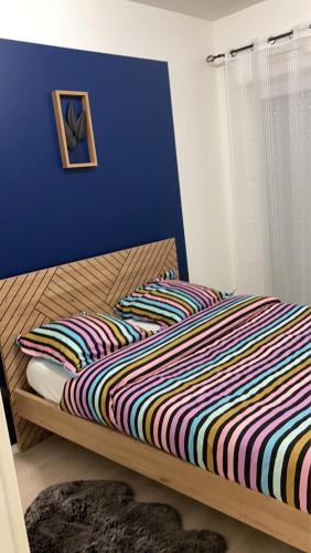 uma cama com um edredão listrado colorido num quarto em Mi appartement mi maison em Guyancourt