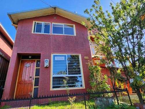 una casa roja con una ventana y una puerta en Hospedaje Mirador Quellón en Quellón