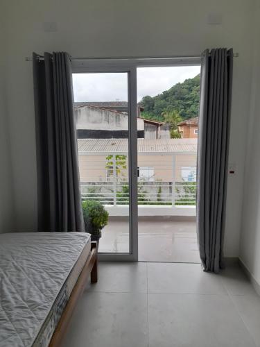 sypialnia z łóżkiem i dużym oknem w obiekcie Moriá Flats w mieście Ubatuba