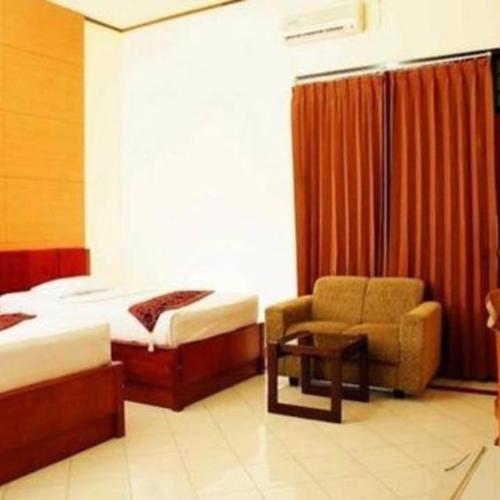 a hotel room with two beds and a chair at Mataram hotel in Tjakranegara