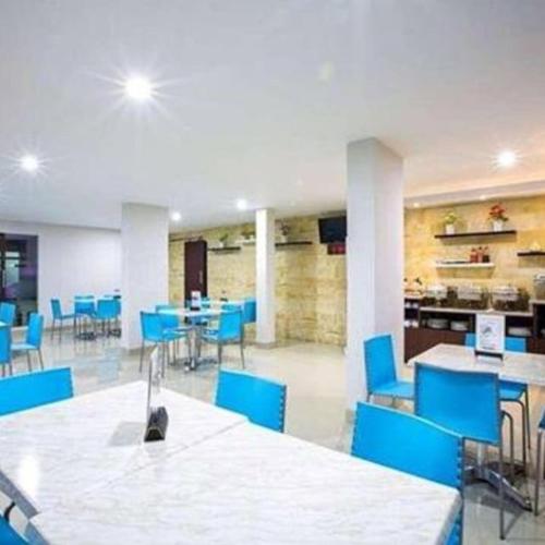 une chambre avec des chaises et des tables bleues et une cafétéria dans l'établissement Mataram hotel, à Tjakranegara