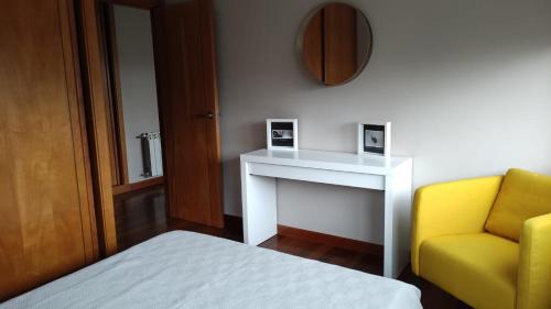 1 dormitorio con 1 cama y 1 silla amarilla en Wanderlust Bastiagueiro, en Perillo