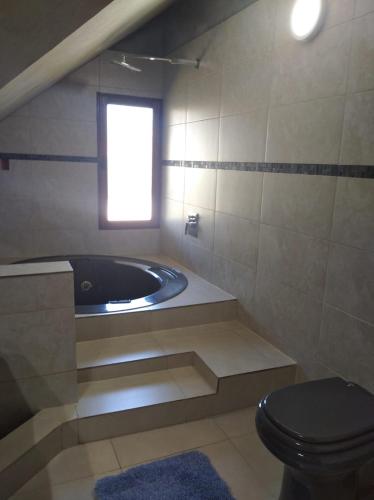 baño con bañera, aseo y ventana en La Casona del Lago, en Balneario Ipora