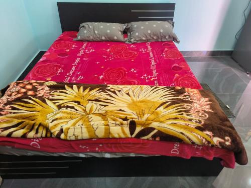 - un lit avec un couvre-lit rouge et des fleurs dans l'établissement Angelina Guest House, à Hyderabad