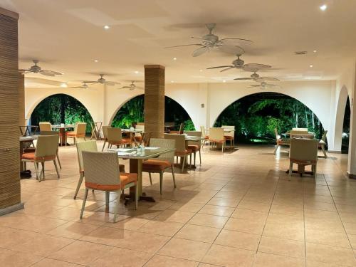 uma sala de jantar com mesas, cadeiras e janelas em GOLF CORONADO LUXURY MANGO SUITE PRIVATE POOL FEE INCLUDED em Playa Coronado