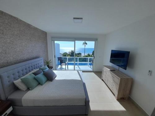 1 dormitorio con cama, TV y balcón en Villas de Playa Blanca, Rooftop Vista al Mar en Río Hato