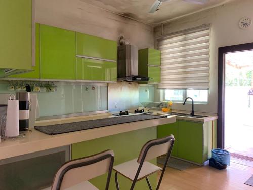 a kitchen with green cabinets and a sink and chairs at The 21 Repoh Homestay in Kangar