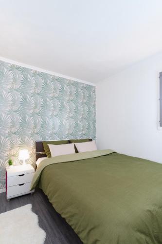 - une chambre avec un lit vert et un mur dans l'établissement Le Cosy : Terrasse • Parking • Piscine • Clim, à Grasse