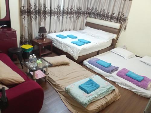 Habitación con 2 camas, sofá y mesa. en Sandakan Game Room-Only, en Sandakan