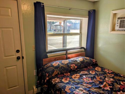 a bedroom with a bed with a window and a bedspread at Tour Inn Motel in Howard City
