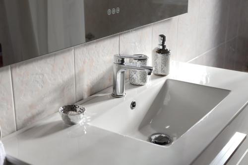 a white bathroom sink with a faucet and a mirror at The Dream Holiday House in Belicena