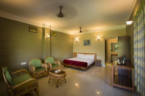 1 dormitorio con 1 cama y sillas en una habitación en SECRET IVORY, en Masinagudi