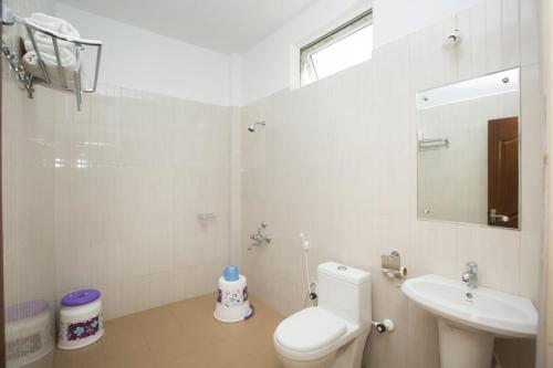 a white bathroom with a toilet and a sink at SECRET IVORY in Masinagudi