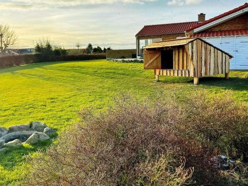 una casa de perros de madera en un campo junto a un edificio en 8 person holiday home in Faaborg, en Bøjden