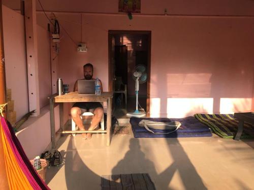 a man sitting at a desk with a laptop at Gokarna Ocean Tree in Gokarna