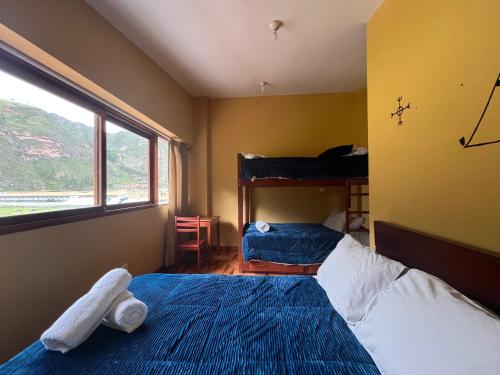 a small bedroom with two beds and a window at El Parche Rutero Hostel in Pisac