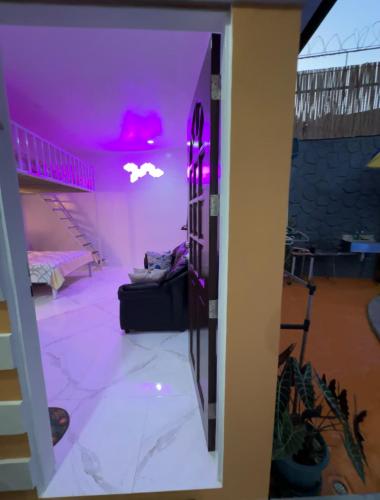 Cozy room with outdoor swimming pool في اولونجابو: غرفة معيشة مع أضواء أرجوانية وأريكة