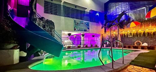 Cozy room with outdoor swimming pool في اولونجابو: حمام سباحة في منزل مع إضاءة أرجوانية وأرجوانية