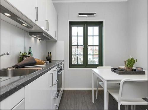 a white kitchen with a table and a window at Studio Apartment Oslo AirPort in Gardermoen