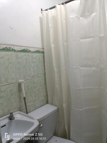 een badkamer met een toilet en een wit douchegordijn bij Townhouse near PH Arena - Ethan's Transient in Marilao