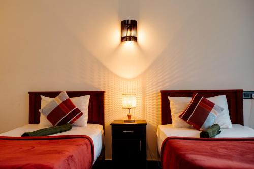 ein Schlafzimmer mit 2 Betten und einer Lampe auf einem Tisch in der Unterkunft Adams Peak Inn in Nallathanniya