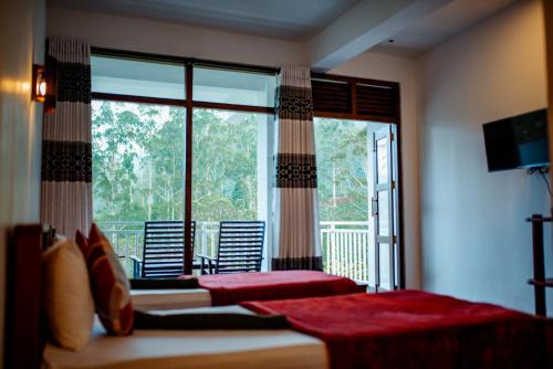 um quarto com 2 camas e uma grande janela em Adams Peak Inn em Nallathanniya